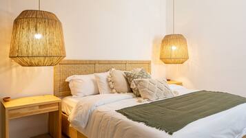 A bedroom with a bed, two bedside tables, a ceiling fan, and two hanging lamps.