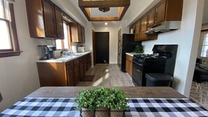 A kitchen with wooden cabinets, a black stove, and a checkered tablecloth with potted plants.