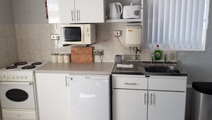 Une cuisine compacte équipée d’une cuisinière, d’un four à micro-ondes, d’un grille-pain et d’un évier situé sous une fenêtre.