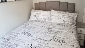 Un lit avec une tête de lit et deux oreillers, chacun orné d’un motif imprimé.