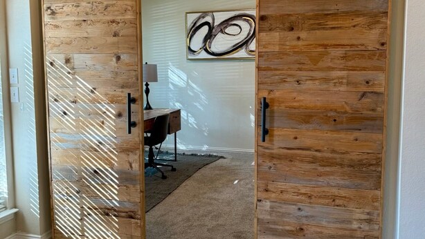 A room with a sliding barn-style door, a desk, and a chair.