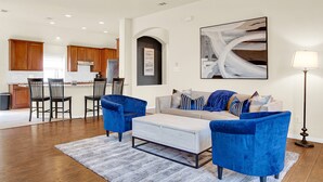 A modern living room with a sofa, two blue armchairs, a coffee table, and a floor lamp.