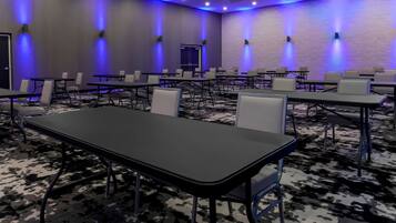 A conference room with tables and chairs, blue ambient lighting, and a patterned carpet.