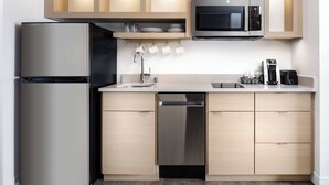 Una cocina moderna con refrigerador, lavavajillas y microondas de acero inoxidable.