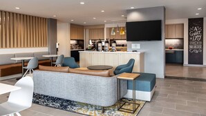 Una cocina moderna con una isla central, una zona de estar con sofá y sillones, y un televisor de pantalla plana montado en la pared.