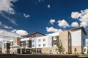 Un hotel moderno con fachada de piedra, un acceso cubierto y un letrero que indica que es un TownePlace Suites by Marriott.