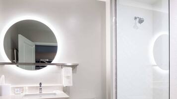 A modern bathroom with a round mirror, a sink, and a toilet.