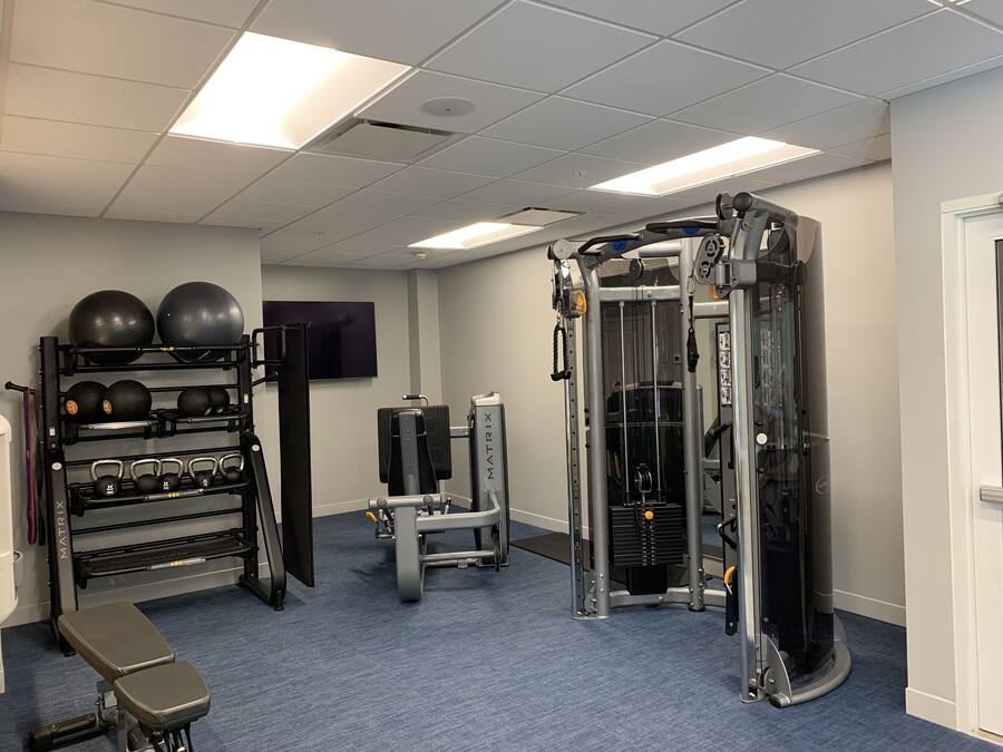 A gym with various exercise equipment, including a squat rack, bench press, and free weights.