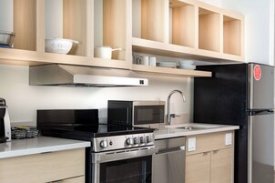 Una cocina moderna con electrodomésticos de acero inoxidable, armarios de madera y un refrigerador negro.