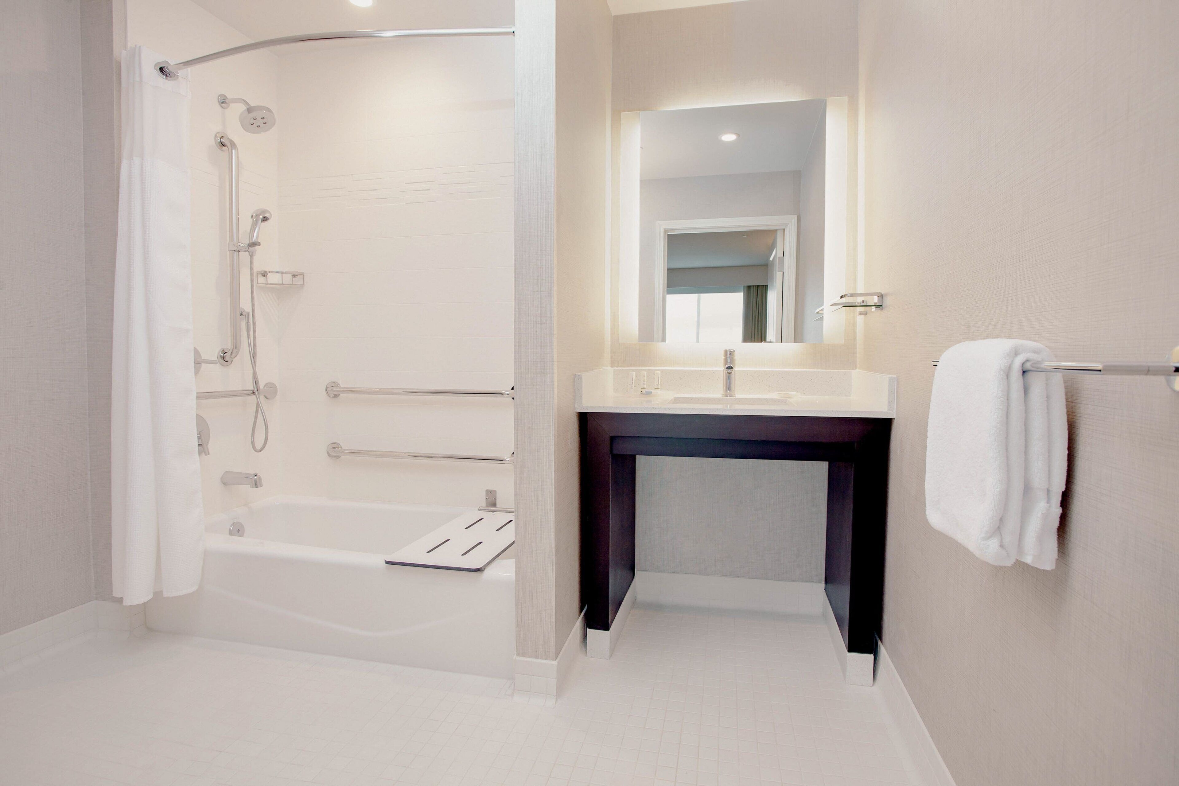 A modern bathroom with a walk-in shower, a bathtub, a vanity with a mirror, and a towel rack.