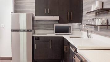 A modern kitchen with dark cabinets, stainless steel appliances, and a marble backsplash.