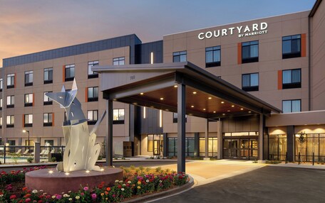 A Courtyard by Marriott hotel with a covered entrance, a pool, and a decorative sculpture.