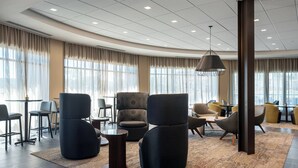 A modern hotel lobby with a large seating area, a patterned rug, and large windows with curtains. - Courtyard by Marriott Petaluma Sonoma County (Petaluma)