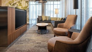 A modern living room with a flat-screen TV, a sofa, armchairs, a coffee table, and a patterned rug. - Courtyard by Marriott Petaluma Sonoma County (Petaluma)