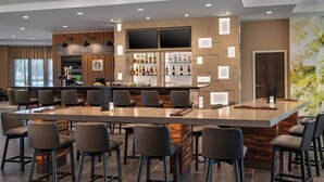 A modern bar area with a long counter, multiple stools, and a variety of liquor bottles. - Courtyard by Marriott Petaluma Sonoma County (Petaluma)