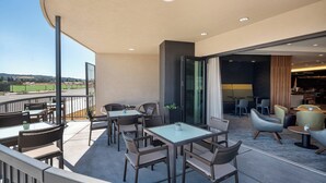 A modern outdoor patio with wicker furniture, glass tables, and a view of the countryside. - Courtyard by Marriott Petaluma Sonoma County (Petaluma)