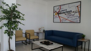 Un área de espera moderna con un sofá azul, dos sillones, una mesa de centro y un mapa en la pared.