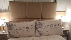 Ein Bett mit einer Bettdecke mit floralem und fahrradbezogenem Muster, zwei passende Kissen und ein Kopfteil.
