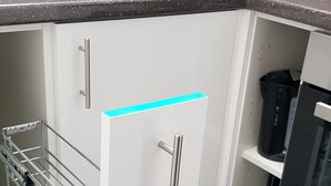 Eine Küche mit Spülbecken aus Edelstahl, weißen Schränken und einem schwarzen Gerät auf der Arbeitsfläche.