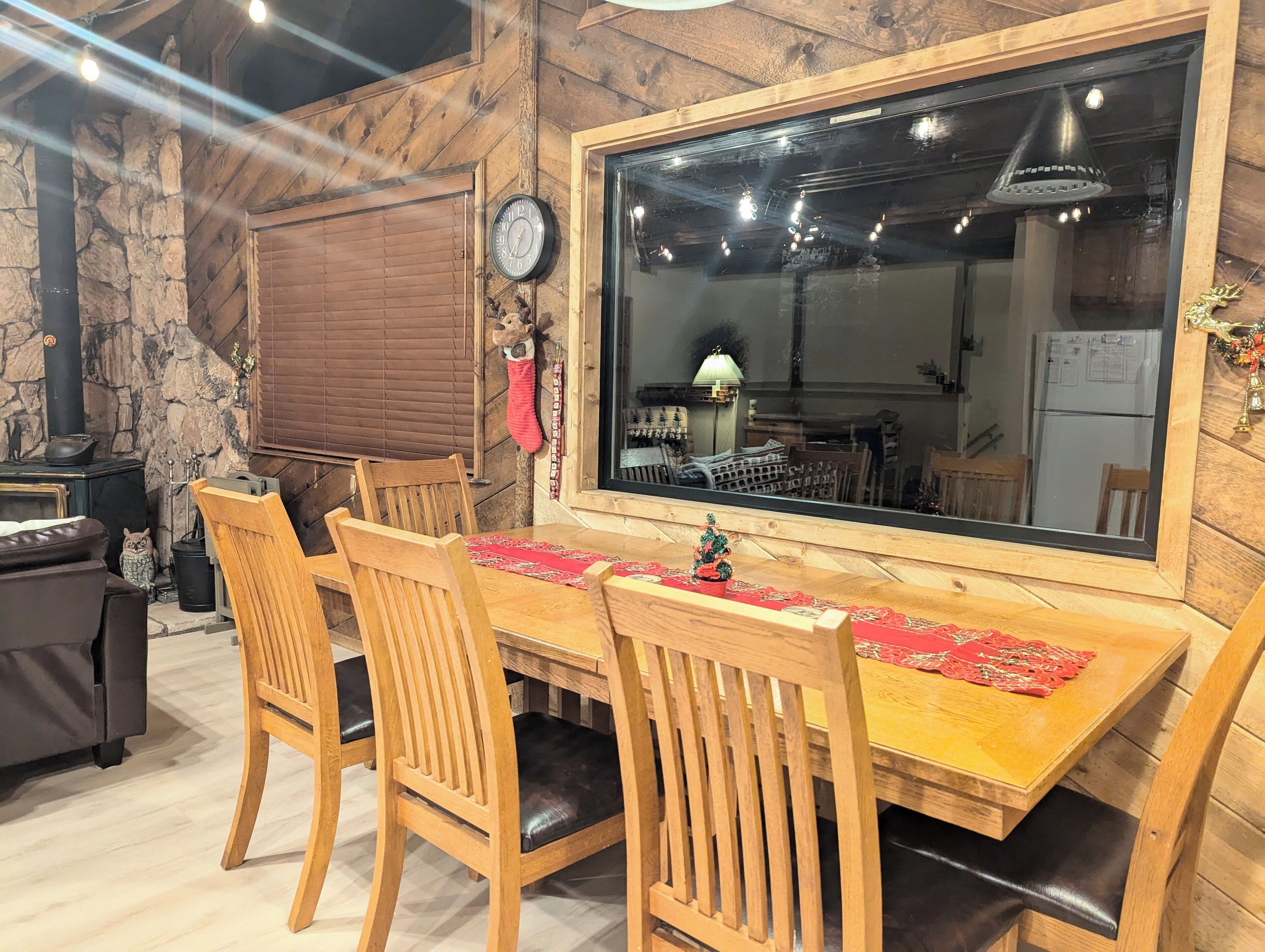 A wooden dining table with four chairs, a large mirror, and a red decorative cloth.
