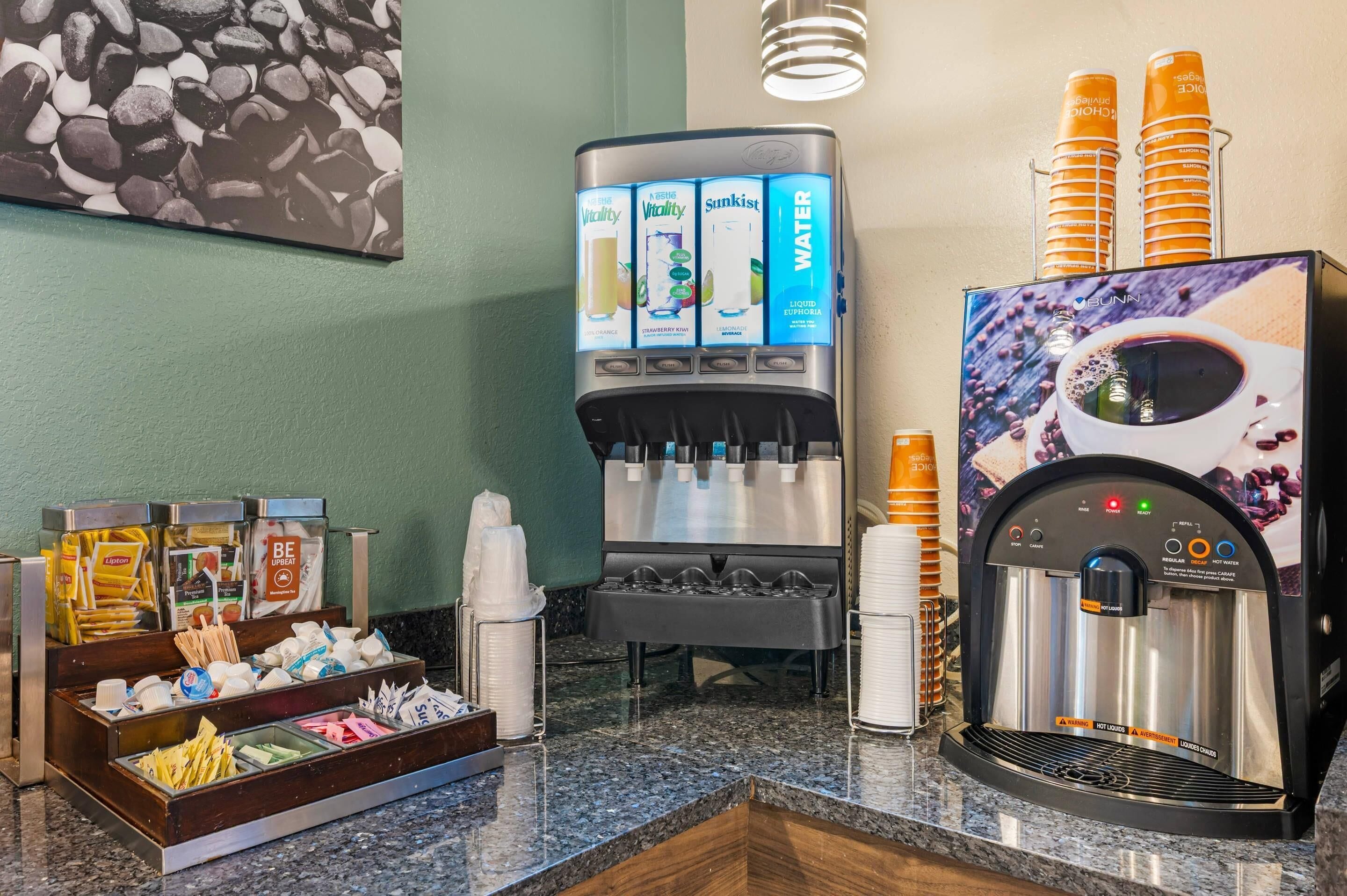 A self-service beverage station with various drink options, including water, juice, and coffee.