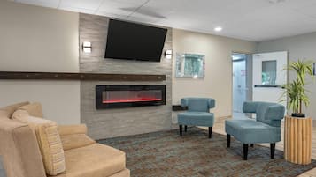 Un hall con chimenea, zona de estar y televisor de pantalla plana en la pared.