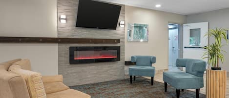 Un hall con chimenea, zona de estar y televisor de pantalla plana en la pared.