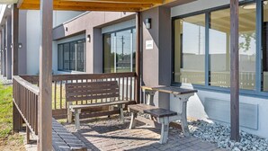 A covered outdoor seating area with wooden benches and a table, adjacent to a building with large windows and a sign indicating a "Designated Smoking Area." - Sleep Inn Indianapolis East (Indianapolis)