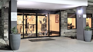 A hotel entrance with a non-smoking sign, a large planter, and a sign indicating surveillance. - Sleep Inn Indianapolis East (Indianapolis)