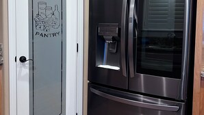 Un réfrigérateur en acier inoxydable doté d ’un distributeur d’eau, une porte blanche avec un panneau en verre et des meubles en bois.