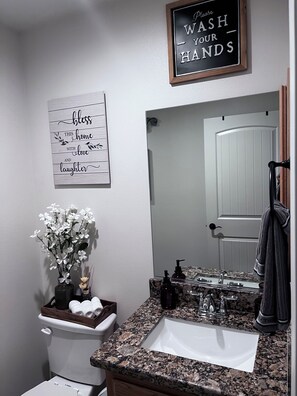 Une salle de bain équipée d’un lavabo, d’un miroir, de toilettes et de panneaux décoratifs au mur.