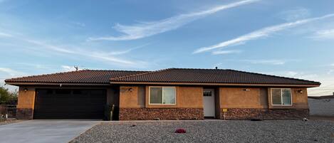 A single-story house with a tiled roof, a garage, and a gravel driveway.