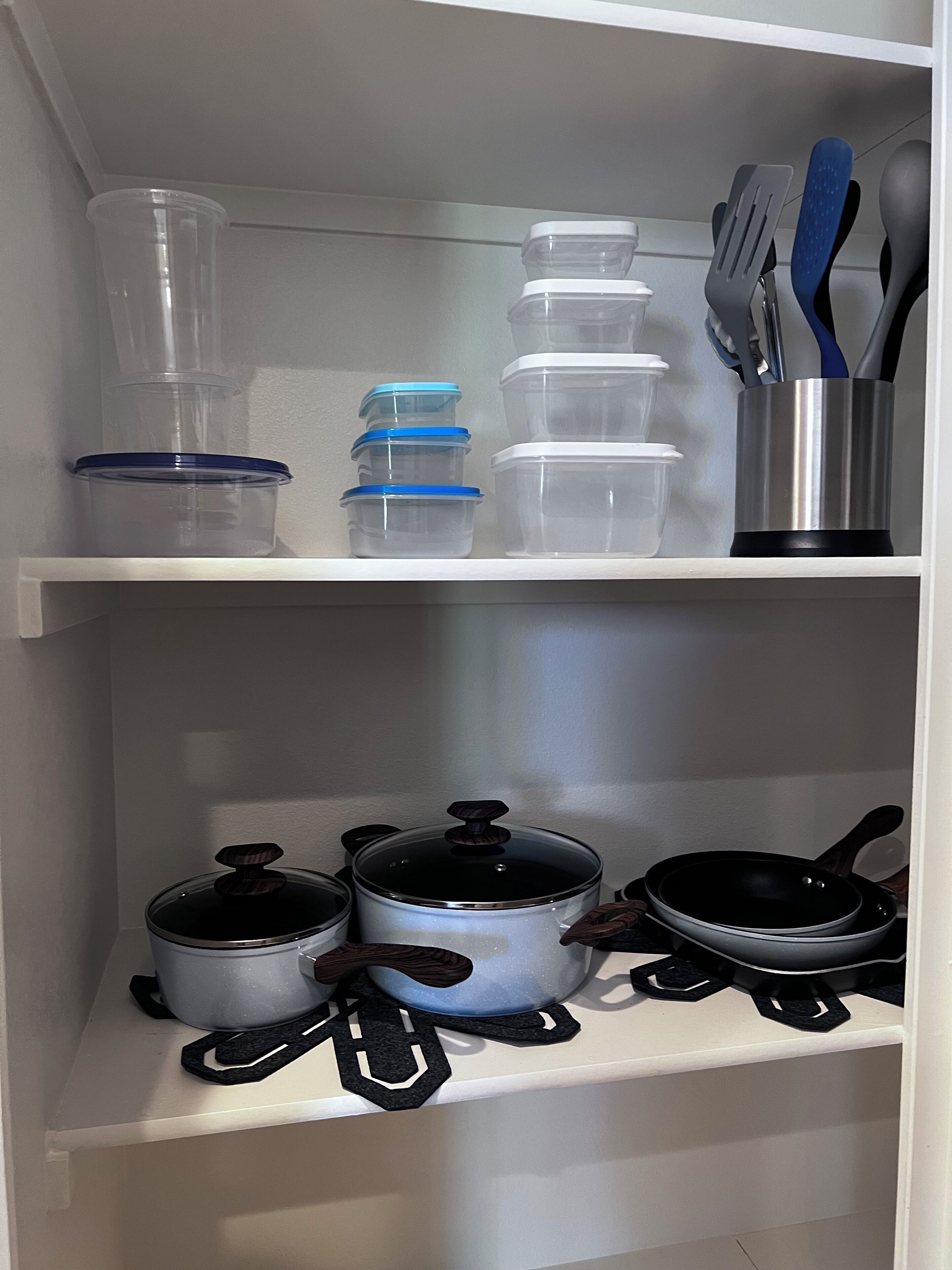 Uma prateleira na cozinha com recipientes de armazenamento, uma panela e uma frigideira.