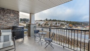 Un balcon avec un mur en pierre, un barbecue et du mobilier d’extérieur.