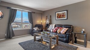 Un salon avec un canapé en cuir, une table basse en verre et une vue sur un immeuble par la fenêtre.