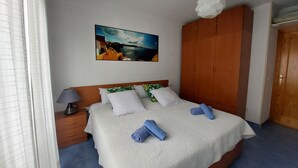 A bedroom with a bed, a nightstand, a wooden wardrobe, a painting on the wall, and a window with curtains. - 90 metres from the beach (PENISCOLA)
