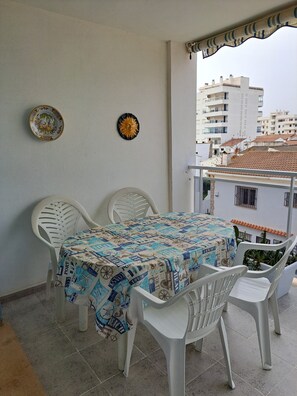 Un balcón con mesa y sillas, dos platos decorativos y vistas a edificios.