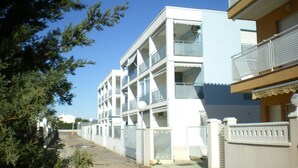 A multi-story residential building with balconies, a gated entrance, and a clear sky. - 90 metres from the beach (PENISCOLA)