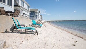 A beachfront property with multiple levels of balconies, a sandy beach, and several blue lounge chairs. - PRIVATE BEACH: BEACHFRONTS & BALCONIES @ NIANTIC W/ 6 QUEENS (East Lyme)