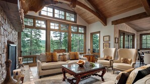 A spacious living room with large windows, a fireplace, and a stone wall.
