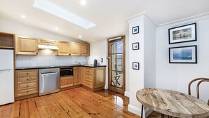 A modern kitchen with wooden cabinets, a dishwasher, and a dining area with a wooden table and chairs.