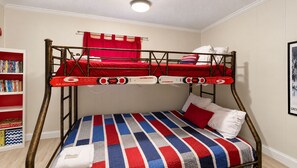 A bunk bed with a red and white striped bedspread, a bookshelf with board games, and a framed picture on the wall. - Summit 108B |3BR,Sunset views, FreeParking (Snowshoe)
