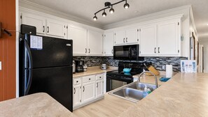 A modern kitchen with white cabinets, a black refrigerator, a microwave, and a stove. - Summit 108B | 3BR | Sunset views | Free Parking (Snowshoe)