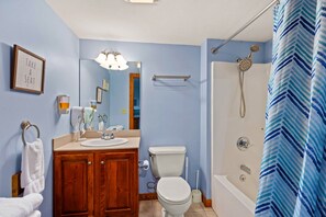 A bathroom with a wooden vanity, a sink, a toilet, a shower with a rain showerhead, and a towel rack. - HH 207: Ski-In/Out | Sunrise Views | Village Steps | Sleeps 4 (Snowshoe)