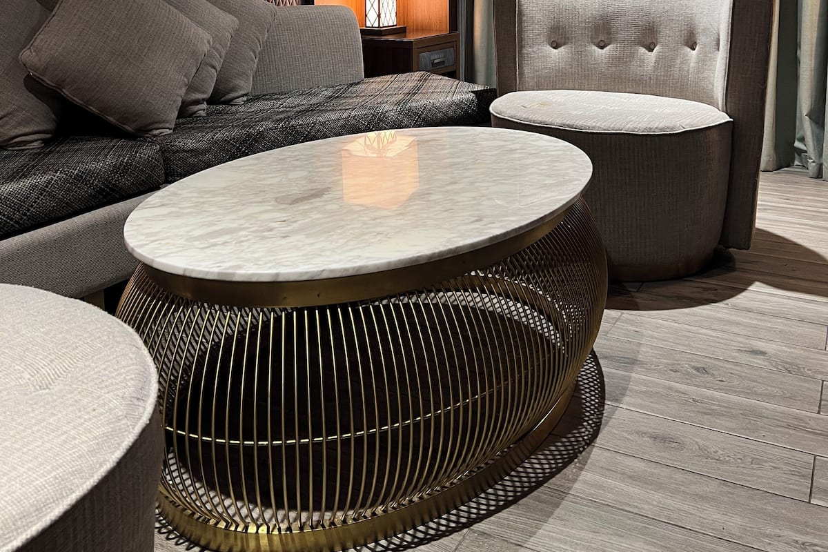 A modern hotel room with a sofa, armchair, and round coffee table.