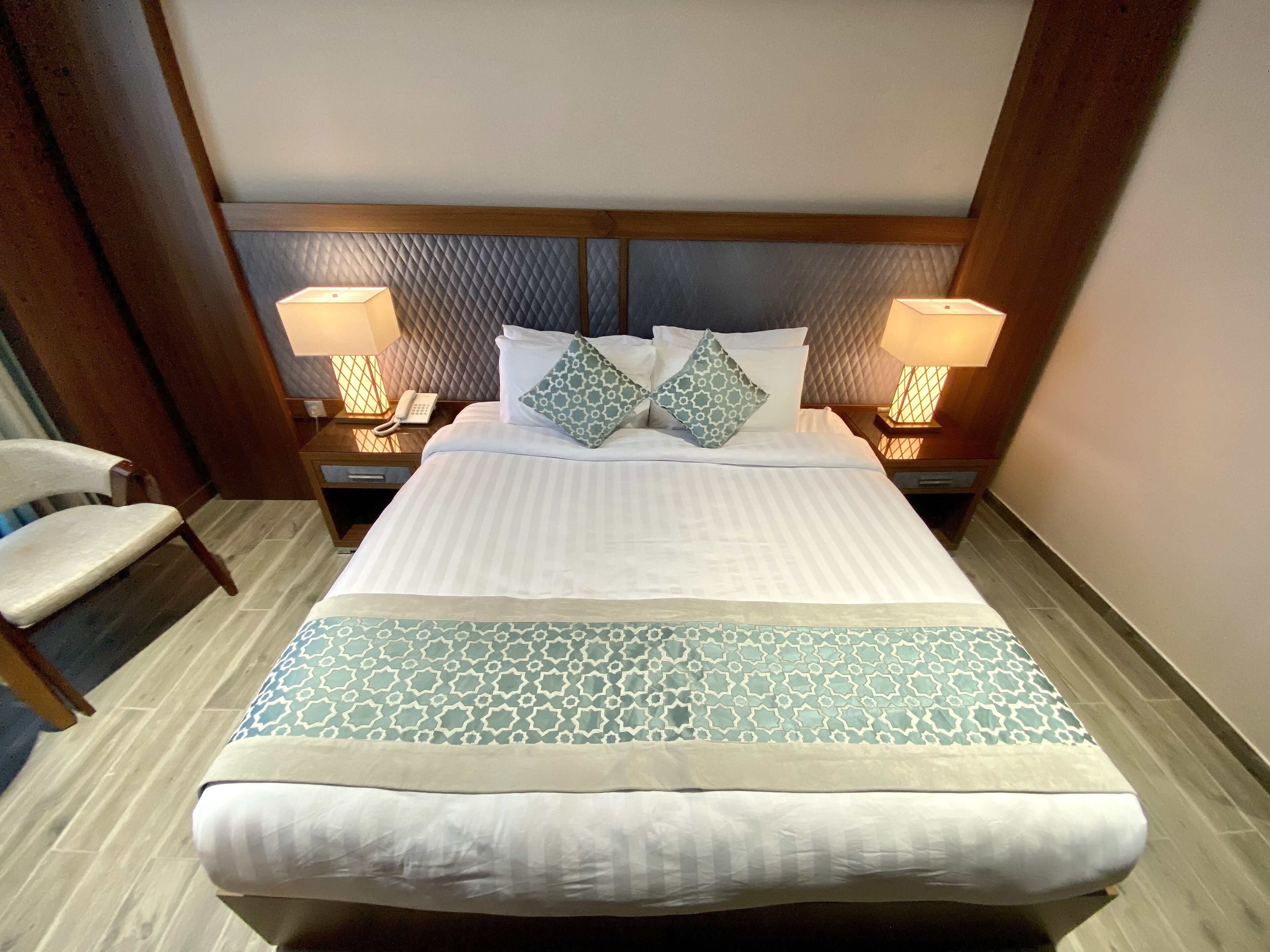 Un lit bien fait, avec une couvre-lit à motifs, deux oreillers et deux lampes de chevet.