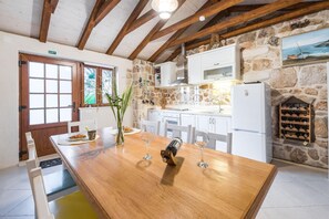 Enjoy meals and drinks in this warm and inviting kitchen, equipped with a dining table, wine rack, and stainless steel range hood.