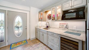 A kitchen with white cabinets, a stainless steel refrigerator, a microwave, and a sink.