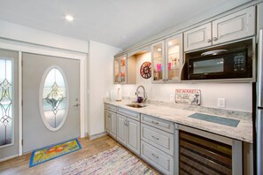 A kitchen with white cabinets, a stainless steel refrigerator, a microwave, and a sink.