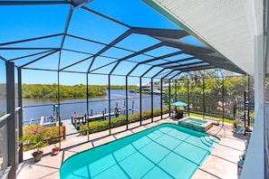 A covered outdoor swimming pool with a view of a lake and dock.